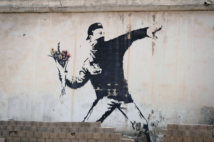 뱅크시의 가장 유명한 작품 중 하나로 꼽히는 &lt;꽃을 던지는 사람&gt;(2003). 팔레스타인 베들레헴 베이트사후르 근처의 쓰레기장 한편에 그렸다. 미술문화 제공