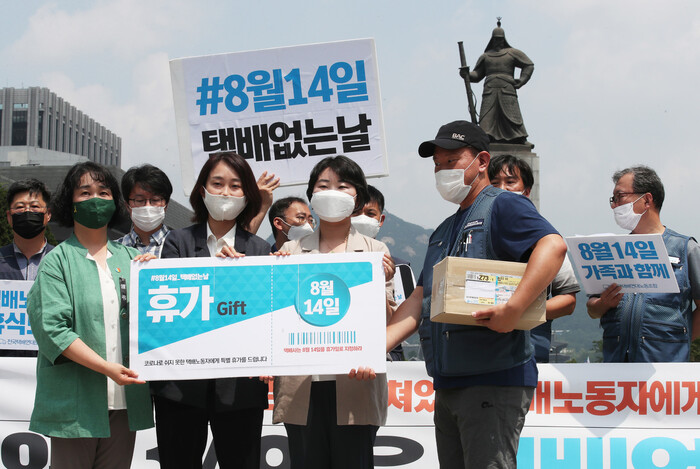 9일 오전 서울 종로구 광화문광장에서 열린 기자회견 ‘8월 14일을 택배없는 날로 지정하라!’에서 참가자들이 택배노동자에게 휴가티켓을 전달하는 행위극을 하고 있다. 백소아 기자 thanks@hani.co.kr