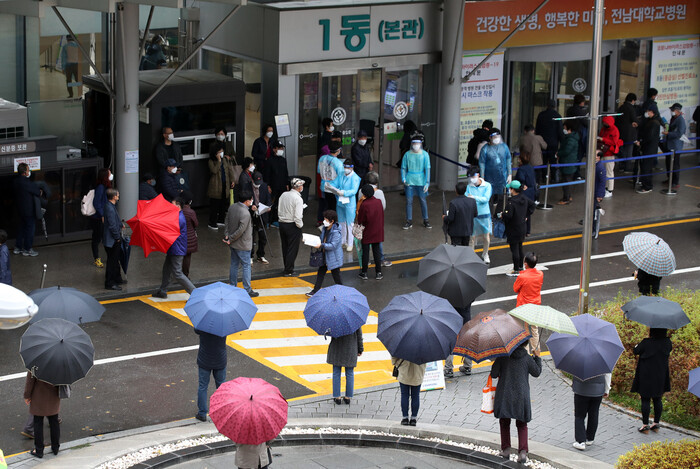 코로나19 확진자의 연이은 발생으로 본관 병실을 폐쇄하고 응급실과 외래 등 진료를 중단한 광주 동구 전남대학교병원에서 19일 오전 처방전을 받으려는 시민들이 본관 앞에서 우산을 쓰고 대기하고 있다. 연합뉴스