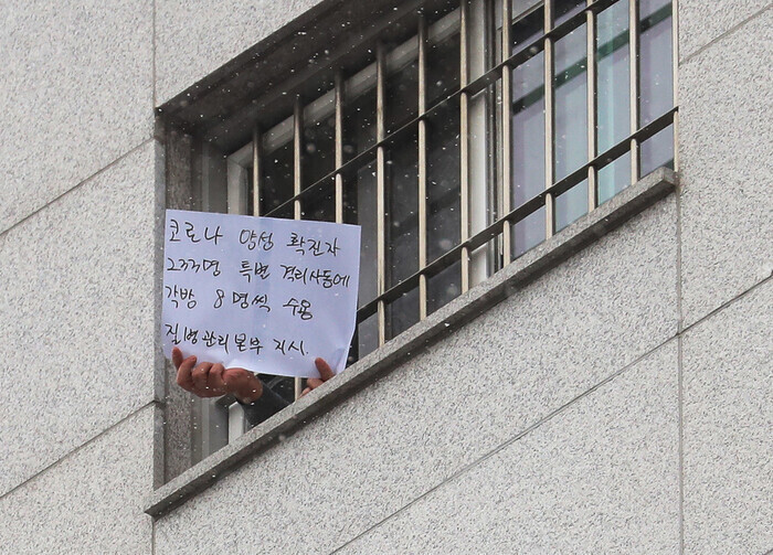 지난해 12월29일 오후 서울 송파구 동부구치소에서 한 수용자가 확진자 과밀수용 등 불만 사항을 직접 적어 취재진을 향해 들어 보이고 있다. 연합뉴스
