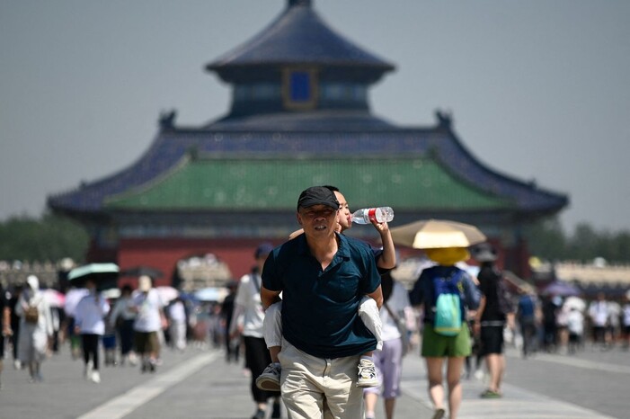 지난달 30일 중국 베이징의 천단공원 방문자 등에 업힌 아이가 물을 마시고 있다. 베이징/AFP 연합뉴스