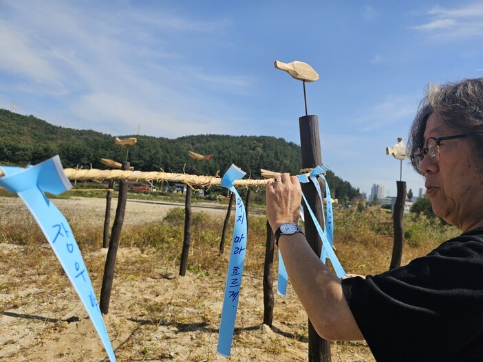 문성호 대전충남녹색연합 상임대표가 솟대에 묶은 금줄에 메시지가 적힌 띠를 달고 있다. 최예린 기자