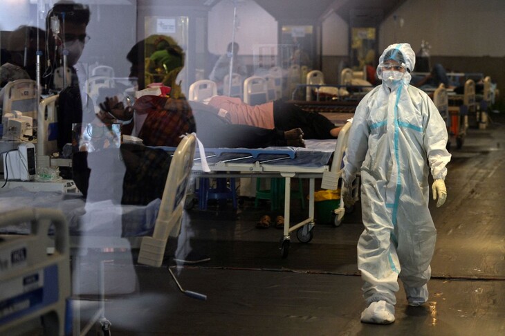 임시 병동으로 개조된 인도 뉴델리의 한 연회장에서 10일(현지시각) 방호복을 입은 의료진이 환자들 옆을 지나가고 있다. 뉴델리/AFP 연합뉴스