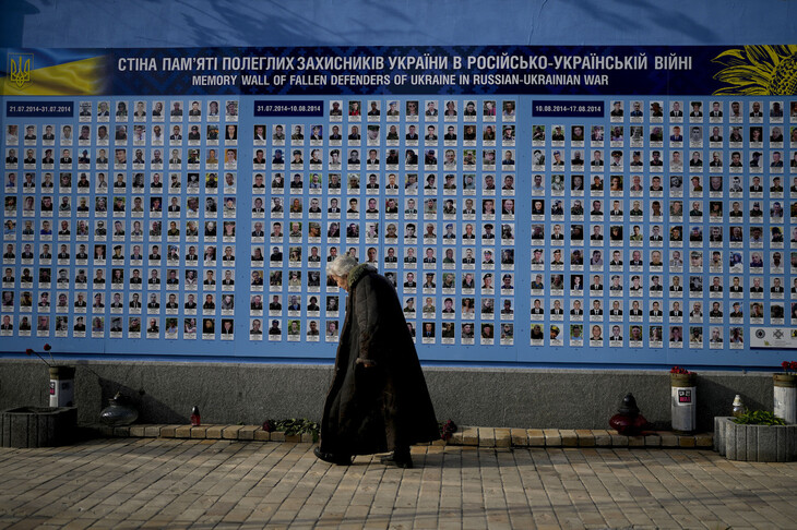 한 노인이 23일(현지시각) 러시아에 맞서 싸우다 숨진 우크라이나인들을 기리기 위해 우크라이나 수도 키이우에 설치된 ‘추모의 벽’ 앞을 지나가고 있다. 키이우/AP 연합뉴스