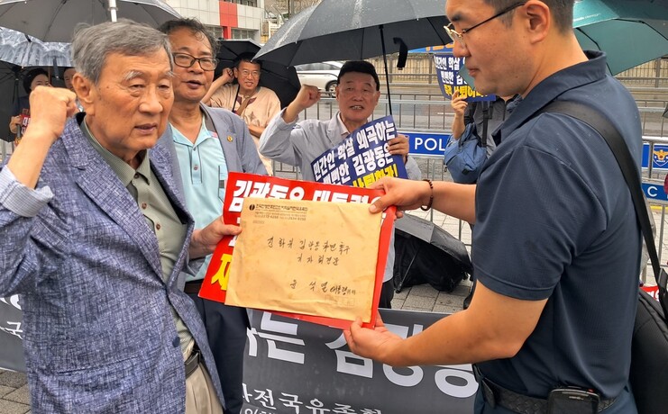 한국전쟁후민간인피학살자전국유족회 윤호상 회장(왼쪽)이 18일 오전 서울 용산 대통령실 앞에서 ‘김광동 진실화해위 위원장 즉각 파면’을 요구하는 집회를 연 뒤 대통령실 관계자에게 관련 서한을 전달하며 구호를 외치고 있다. 사진 고경태 기자