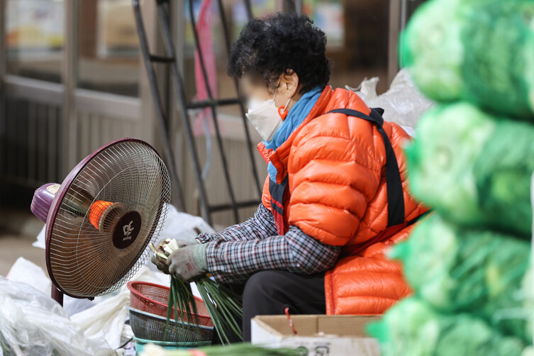 서울 최저 기온이 영하 8도까지 떨어지며 추운 날씨를 보인 30일 오전 서울 시내 한 시장에서 상인이 난로를 켜고 영업을 하고 있다. 연합뉴스