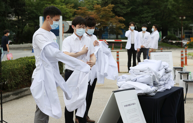 23일 오전 서울 종로구 서울대병원 대학의원 본관 앞에서 의과대학 정원 확대 등 정부 정책에 반대하는 전공의들이 의사 가운을 벗고 있다. 연합뉴스
