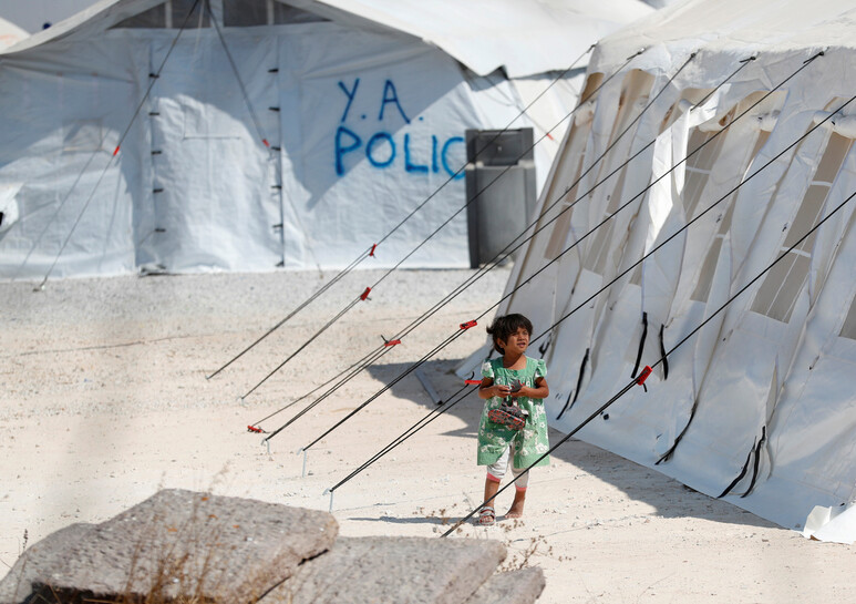 그리스 레스보스섬 난민캠프가 지난 8~9일 화재로 전소된 뒤 새로 지어진 임시 텐트 앞을 지난 21일 한 아이가 지나가고 있다. 레스보스/로이터 연합뉴스