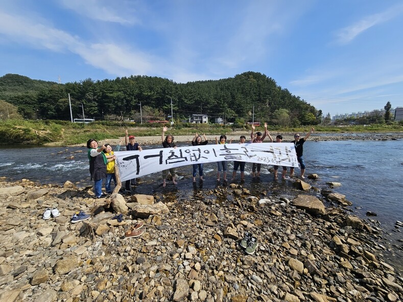 대전충남녹색연합과 대전환경운동연합 회원들이 지난 12일 철거된 태봉보 자리에서 ‘거침없이 흘러라’라고 적힌 펼침막을 들고 환호하고 있다. 최예린 기자