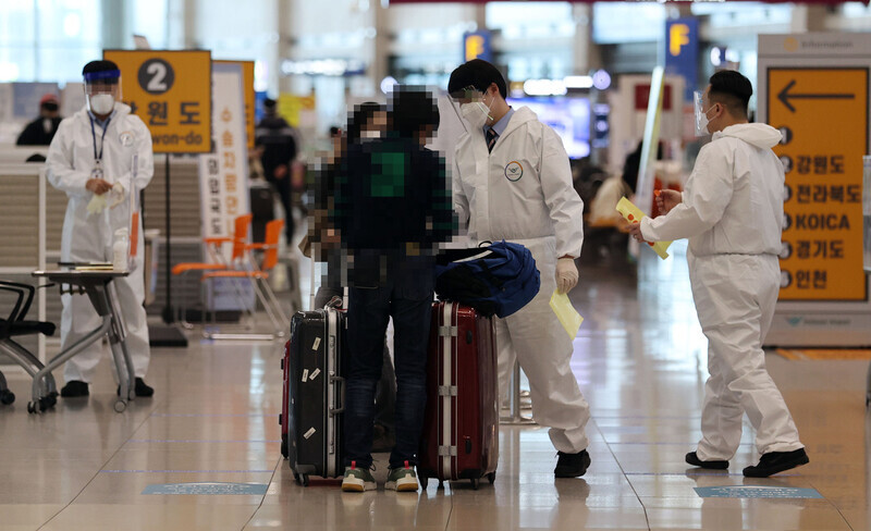 지난해 12월27일 인천국제공항 제1터미널 입국장에서 방역 관계자들이 입국자들에게 동선을 안내하고 있다. 연합뉴스