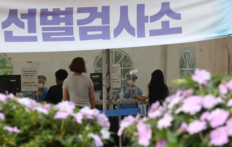 지난 18일 오후 꽃길이 조성된 서울 마포구 서강대역사 광장 임시선별검사소에서 시민들이 검사를 위해 의료진과 대화하고 있다. 서울시는 대학로와 이태원 등 침체 상권을 비롯한 시내 34곳에 꽃길을 조성한다고 이날 밝혔다. 연합뉴스
