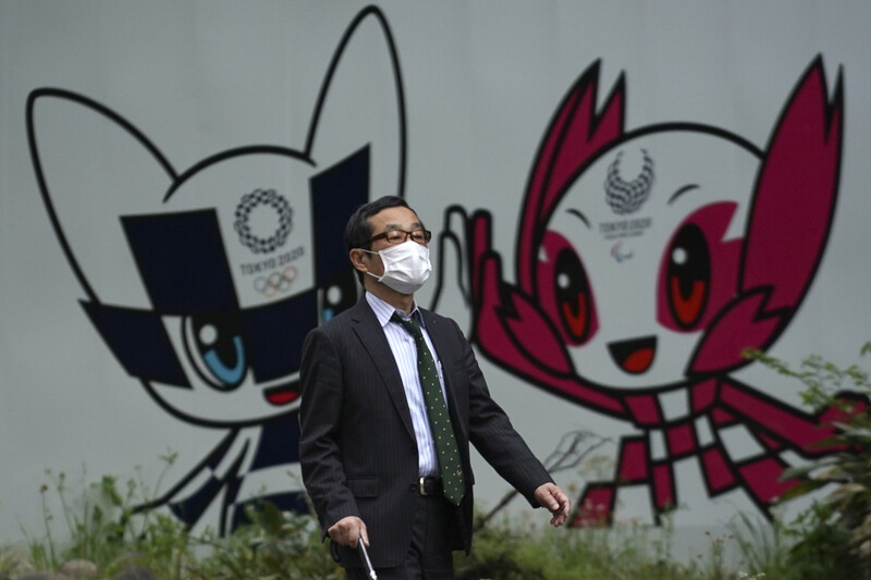 A masked citizen walks the streets of Tokyo on the 28th. After that, you will see Miraitowa (left) and Somatei, the mascots of the Tokyo 2020 Olympic and Paralympic Games. Tokyo / AP Yonhap News