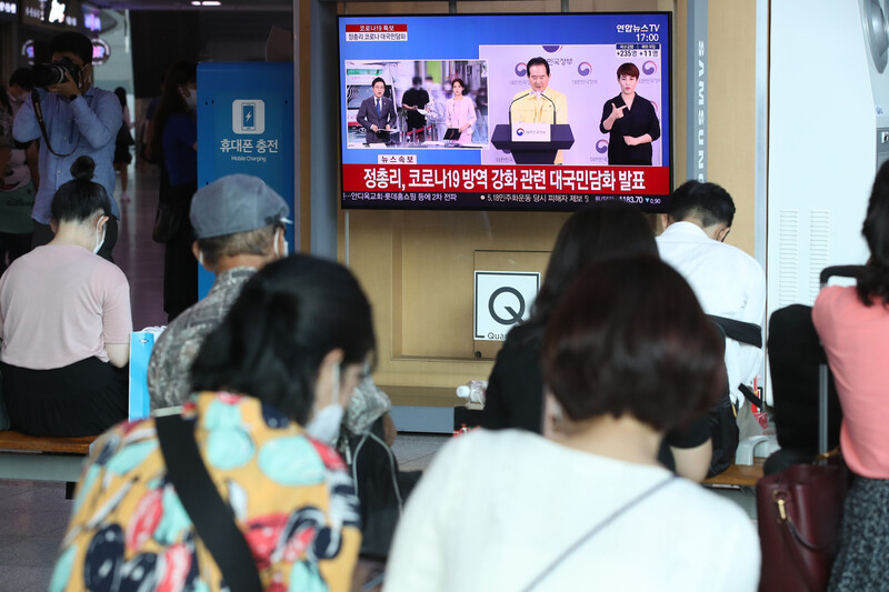 18일 오후 서울역 대합실에서 시민들이 정세균 국무총리 코로나19 방역 강화 방안 관련 대국민 담화 발표를 시청하고 있다. 연합뉴스