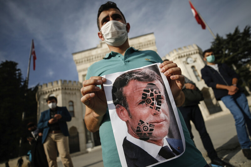 25일 터키 이스탄불에서 한 청년이 에마뉘엘 마크롱 프랑스 대통령의 얼굴에 구두발자국이 찍힌 사진을 들고 있다. 이스탄불/AP 연합뉴스