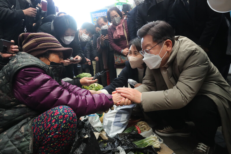 더불어민주당 이재명 대선후보 부부가 12일 오전 경북 예천군 예천읍 상설시장을 방문해 좌판에서 냉이를 사며 할머니의 손을 꼭 잡고 있다. 연합뉴스