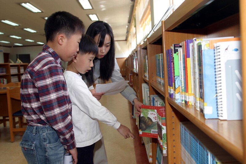 한 초등학교 도서관 열람실에서 사서가 학생들에게 책을 골라주고 있다. 연합뉴스