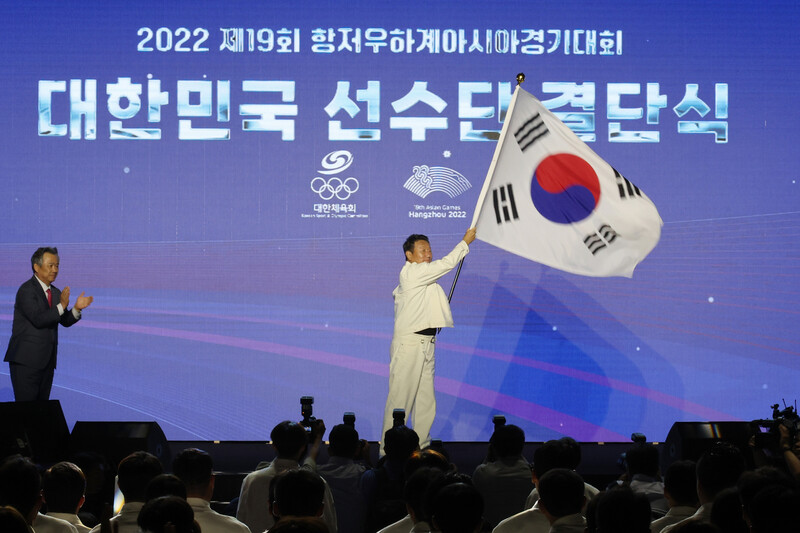 최윤 항저우아시안게임 대한민국 선수단장이 12일 서울 송파구 올림픽공원 올림픽홀에서 열린 선수단 결단식에서 단기를 흔들고 있다. 연합뉴스