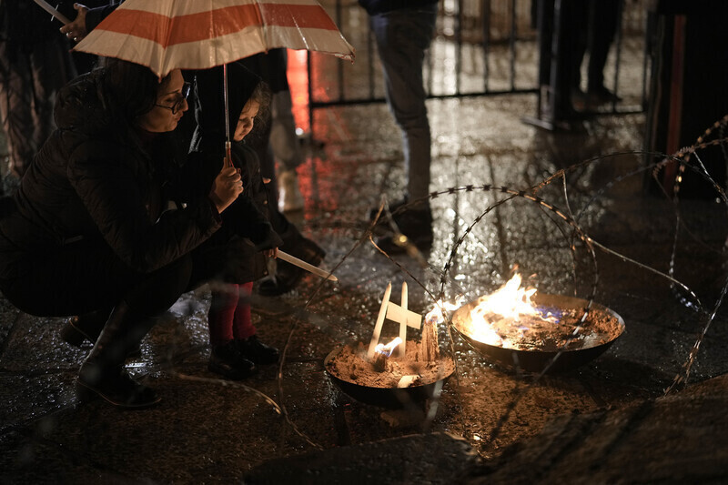 지난 12월23일(현지시각) 팔레스타인 서안지구 베들레헴의 구유 광장에서 한 여성과 어린이가 전쟁 희생자들을 추모하기 위해 촛불을 켜고 있다. AP 연합뉴스