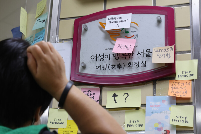 지난 20일 오전 한 시민이 신당역 여자화장실 입구에 부착된 팻말 주변에 붙은 메시지를 보고 있다. 연합뉴스
