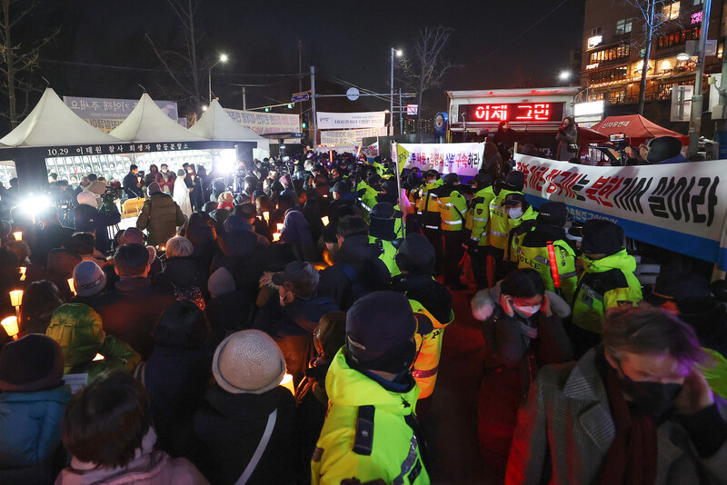 지난 12월25일 오후 서울 용산구 녹사평역 광장에 마련된 이태원참사 희생자 시민분향소에서 천주교 정의구현전국사제단 소속 신부들이 참사 희생자와 유가족을 위한 성탄대축일 미사를 집전하는 가운데(왼쪽) 보수 단체가 집회를 하고 있다. 연합뉴스