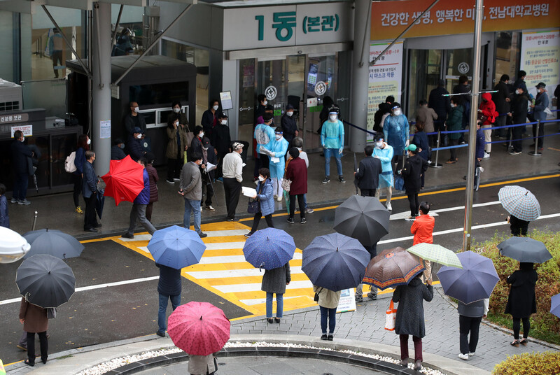 코로나19 확진자가 잇따라 발생해 본관 병실을 폐쇄하고 응급실과 외래 등 진료를 중단한 광주 동구 전남대학교병원에서 19일 오전 처방전을 받으려는 시민들이 본관 앞에서 우산을 쓰고 대기하고 있다. 연합뉴스