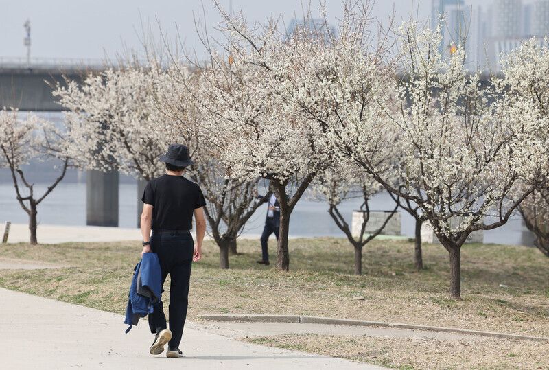 지난달 22일 오후 서울 여의도 한강공원에서 한 시민이 외투를 벗은 채 걸어가고 있다. 연합뉴스