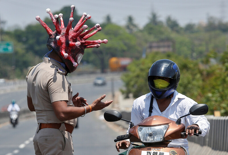 인도 정부가 코로나19 확산을 막기 위해 3주간 ‘국가 봉쇄령’을 내린 뒤, 28일 첸나이에서 한 경찰이 코로나19 모습을 본 따 만든 헬멧을 쓴 채 오토바이 운전자에게 집으로 돌아가라고 얘기하고 있다. 첸나이/로이터 연합뉴스
