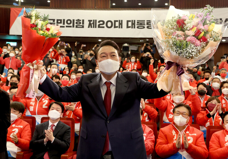 윤석열 대통령 당선인이 10일 새벽 서울 여의도 국회도서관에 마련된 '국민의힘 제20대 대통령선거 개표상황실'을 찾아 꽃다발을 받은 뒤, 취재진을 향해 포즈를 취하고 있다. 국회사진기자단