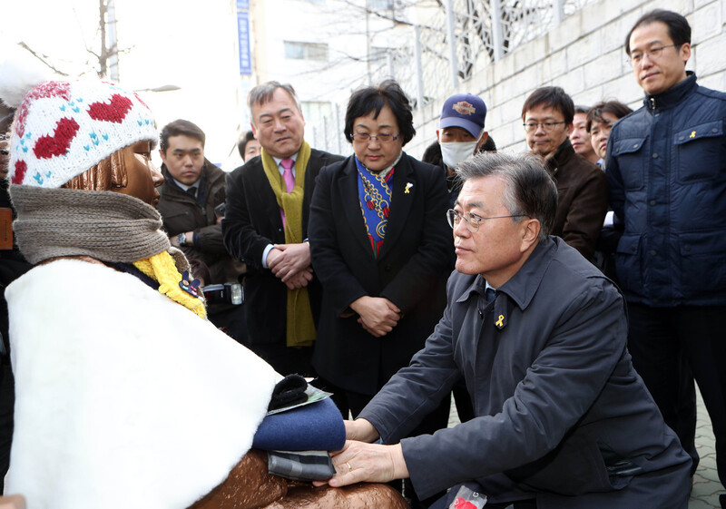 문재인 대통령이 집권 전인 2017년 1월 부산 동구 일본영사관 앞에 있는 ‘평화의 소녀상’을 찾아가 손을 잡고 있다. 문 대통령은 대선 기간 중에 나온 책 &lt;운명에서 희망으로&gt;에서 일본군 ‘위안부’ 문제에 대해 “이 문제를 포함한 과거사 문제는 우리로선 어쨌든 지속적으로 일본에 요구해야 할 내용”이라고 말했다.부산/연합뉴스