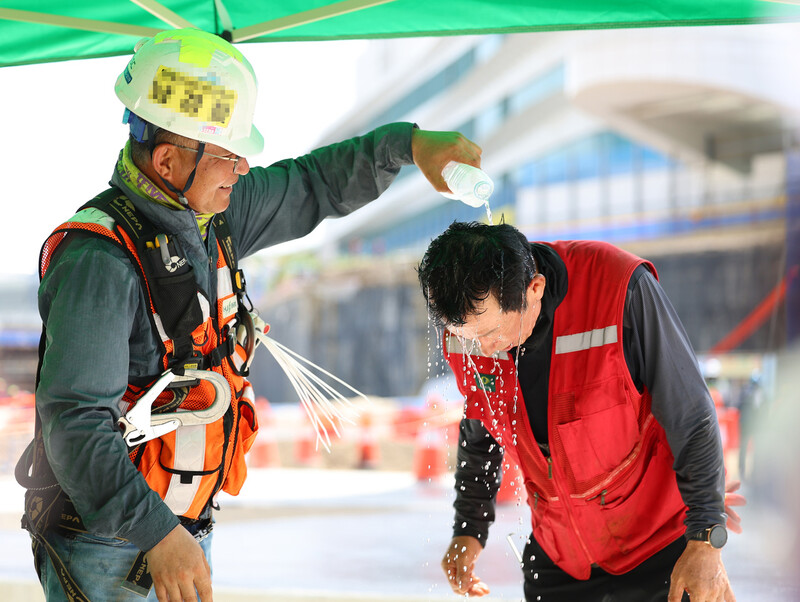 2일 오전 인천국제공항 제2터미널 제2합동청사 확장 건설현장 쉼터에서 근로자가 다른 근로자의 머리에 물을 뿌려주고 있다. 연합뉴스