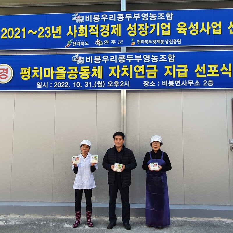 전북 완주군 비봉우리콩두부 영농조합법인 마을기업 공장 앞에서 조한승 법인 대표(가운데), 조영순 공장장(왼쪽) 등이 콩으로 만든 제품을 들고 서 있다. 완주군 제공