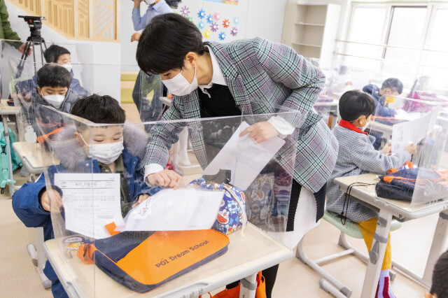 지난 2일 오전 서울시 강남구 포이초등학교에서 첫 등교를 한 1학년 학생들이 담임교사로부터 알림장을 받고 있다. 사진공동취재단