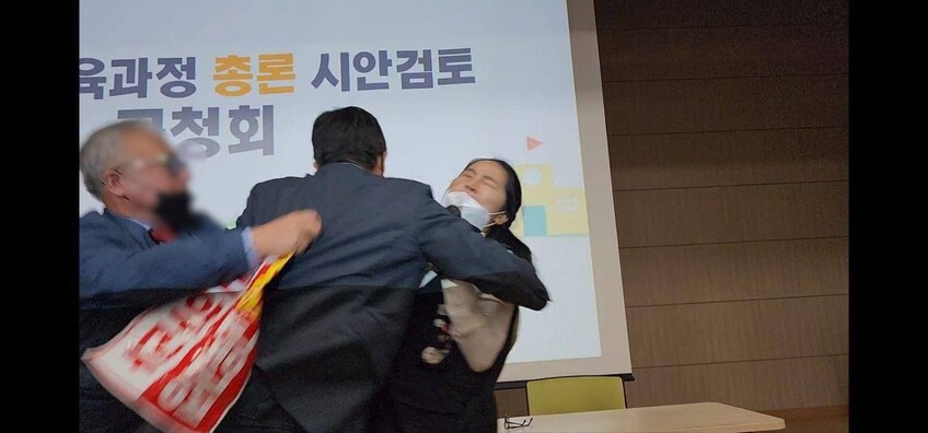 8일 오후 충북 청주시 한국교원대 종합교육연수원 문화관에서 열린 ‘2022 개정 교육과정’ 총론 시안 공청회에서 최서현 전국특성화고노동조합 위원장이 연단에 올라 발언을 하는 도중 보수 단체 회원으로 보이는 남성이 난입해 최 위원장에게 달려들고 있다. 사진 전국특성화고노동조합 제공