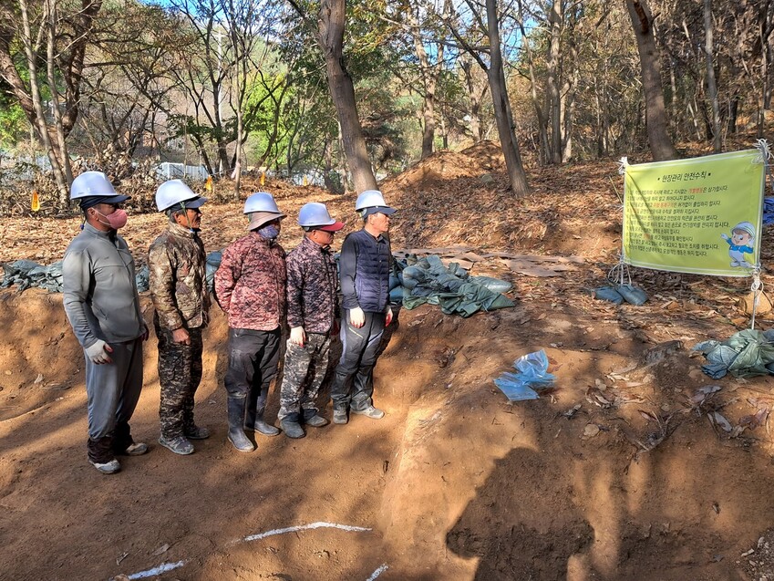 유해발굴에 참여한 인부들이 작업 시작 직전 함께 모여 현장관리 안전수칙을 보고 있다. 고경태 기자