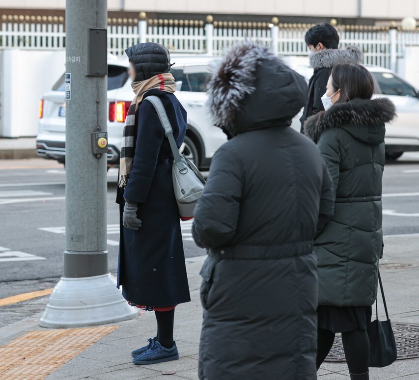 서울 시민들이 종로구 광화문역 인근에서 외투 모자를 쓰고 신호를 기다리고 있다. 연합뉴스