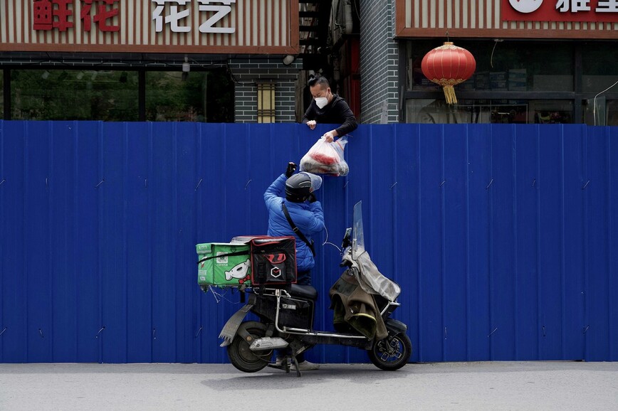 지난 11일 중국 베이징에서 한 배달원이 통제구역 주민에게 물품을 전달하고 있다. 베이징/AFP 연합뉴스