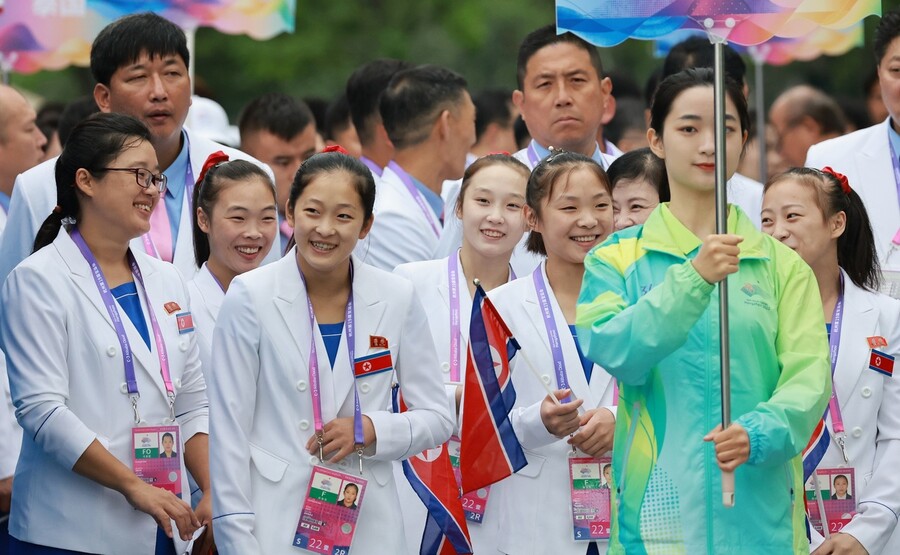 2022 항저우아시안게임 개막을 하루 앞둔 지난 22일 중국 항저우시 아시안게임 선수촌 국기광장에서 열린 공식 입촌식에서 안창옥(왼쪽 세 번째), 김손향(왼쪽 다섯 번째) 등 북한 기계체조 선수단이 입장을 기다리며 대화하던 중 미소 짓고 있다. 항저우/연합뉴스