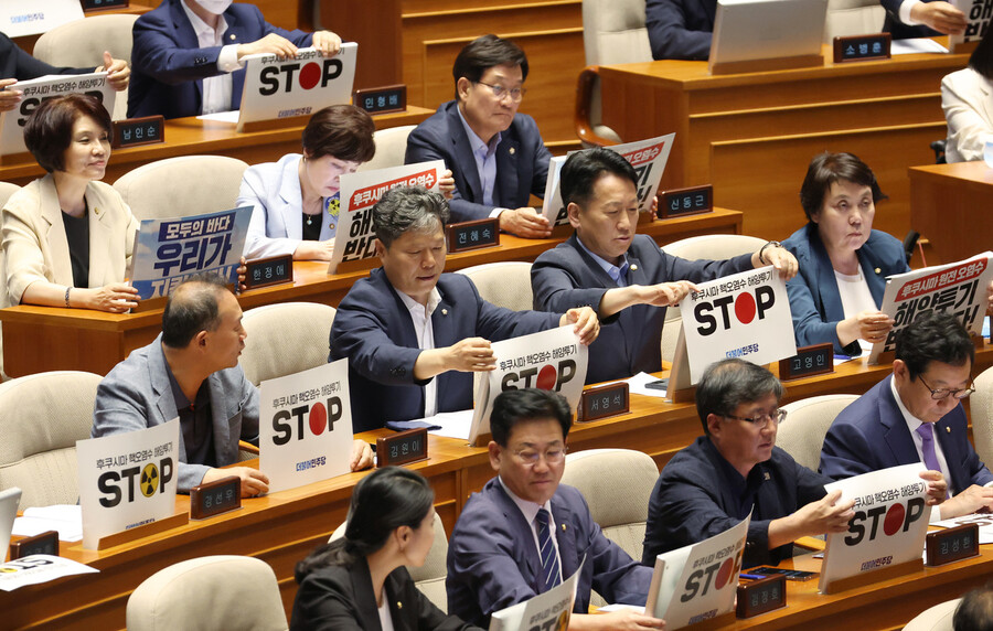 24일 오후 국회에서 열린 본회의에서 더불어민주당 의원들이 일본 정부의 후쿠시마 오염수 방류를 규탄하는 피켓을 붙이고 있다. 연합뉴스