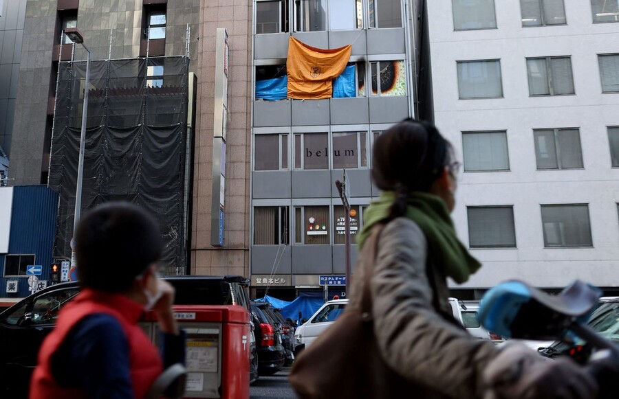 지난 17일 오전 일본 오사카 기타구에 있는 8층짜리 건물 4층에 있는 병원에서 방화로 추정되는 화재가 발생해 24명이 숨졌다. 18일 건물 앞을 사람들이 지나가고 있다. 오사카/AFP 연합뉴스