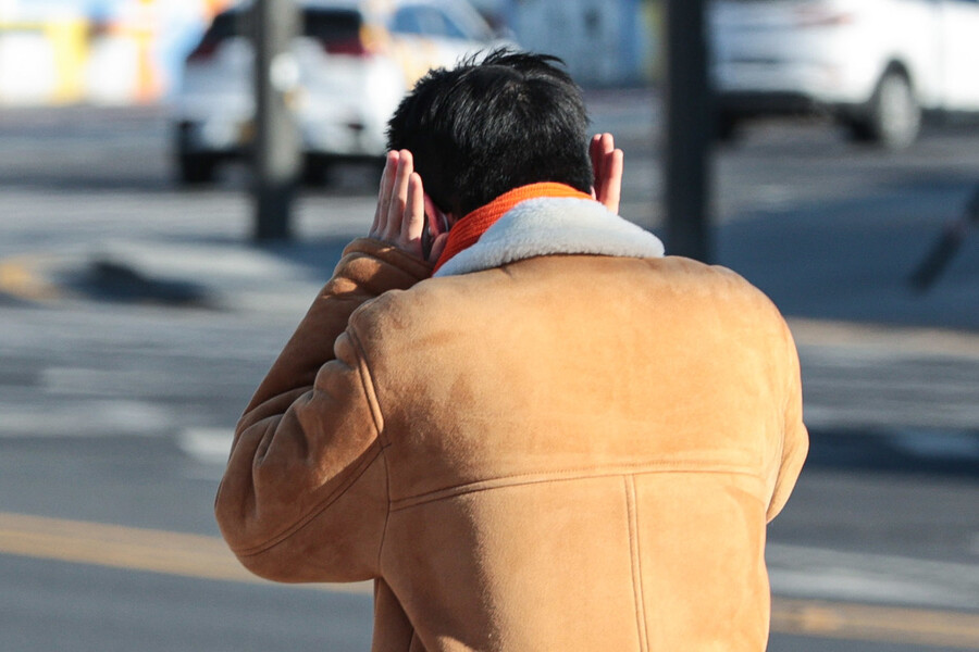 설 연휴 마지막 날인 24일 서울 종로구 광화문광장에서 한 시민이 차가운 바람이 불자 귀를 막으며 걷고 있다. 연합뉴스