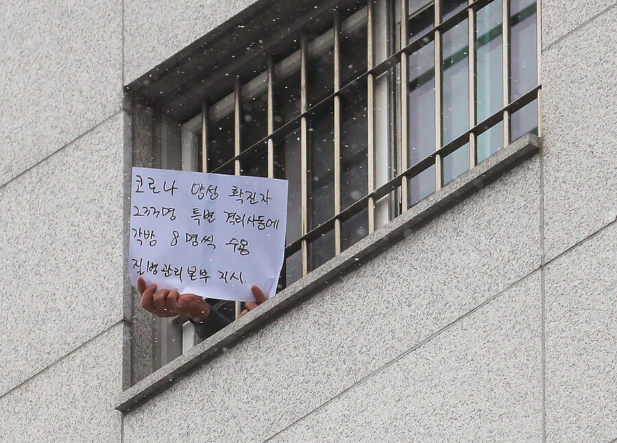 29일 오후 서울 송파구 동부구치소에서 한 수용자가 방 창문으로 확진자 과밀수용 등 불만 사항을 직접 적어 취재진을 향해 들어 보이고 있다. 연합뉴스