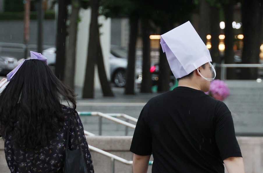 지난 18일 오후 갑자기 비가 내려 우산을 미리 챙기지 못한 시민이 쇼핑백으로 비를 가린 채 서울역 인근 거리를 지나고 있다. 연합뉴스