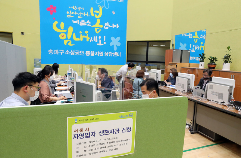 서울시가 ‘자영업자 생존자금’ 신청 접수를 온라인에서 시작한 첫날인 25일 서울 송파구청 소상공인 종합지원 상담센터에서 구청 관계자들이 방문자들과 상담하고 있다. 연합뉴스