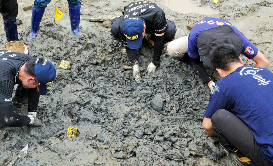 2014년 8월21일 전북경찰청 과학수사대(CSI) 직원들이 전북 망성면 화산리 황산대교 아래 금강변에서 유해를 발굴하고 있다. 발굴 당시엔 “경찰들이 한국전쟁 당시 숨진 선배 경찰관들의 유해를 발굴하고 있다”는 사진 설명이 실렸다. 연합뉴스