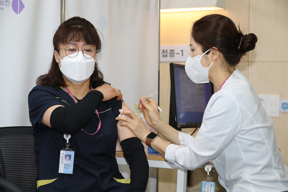 27일 서울시 중구 을지로 국립중앙의료원 중앙예방접종센터에서 청소노동자 정미경씨가 화이자 백신 1호 접종을 받고 있다. 사진공동취재단