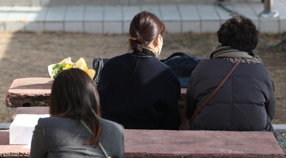 15일 경남 김해시 대중초등학교에서 열린 초교·병설 유치원 비대면 졸업 및 수료식에서 학부모들이 교실 밖 의자에 앉아 휴대전화기로 졸업식 상황을 지켜보고 있다. 이날 졸업식은 가족 등 지인 참석 없이 진행됐다. 연합뉴스