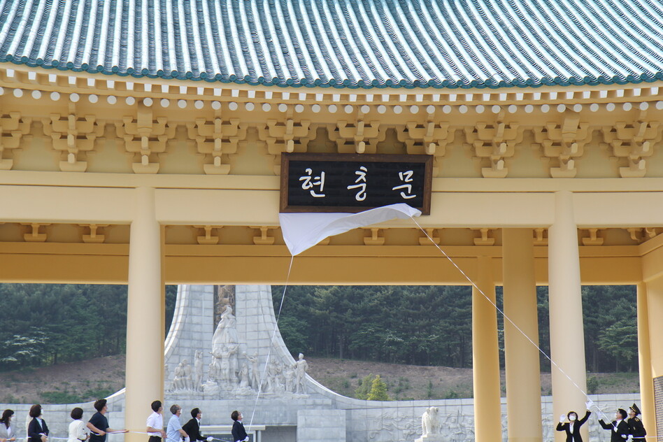 국립대전현충원이 29일 현충원 현판 ‘현충문’을 새 현판으로 교체한 뒤 제막을 하고 있다. 현충원은 그동안 전두환 전 대통령의 친필 현판이 걸려 있었지만 이날 ‘안중근체’로 제작한 새 현판을 달았다.