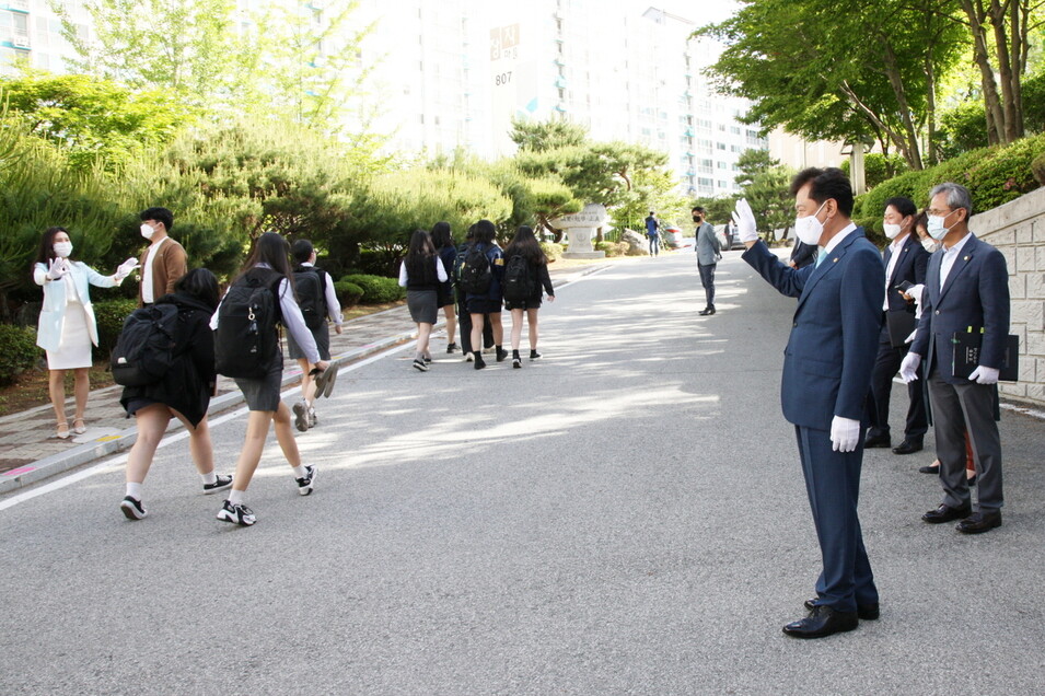 김병우 충북교육감(오른쪽 손 흔드는 이)이 20일 오전 청주 금천고등학교에서 등교하는 학생들에게 손을 흔들고 있다.