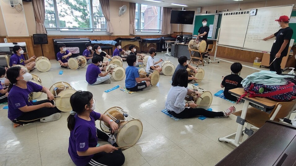 신석초등학교 아이들이 노름마치예술단 단원들에게서 장구를 배우고 있다.