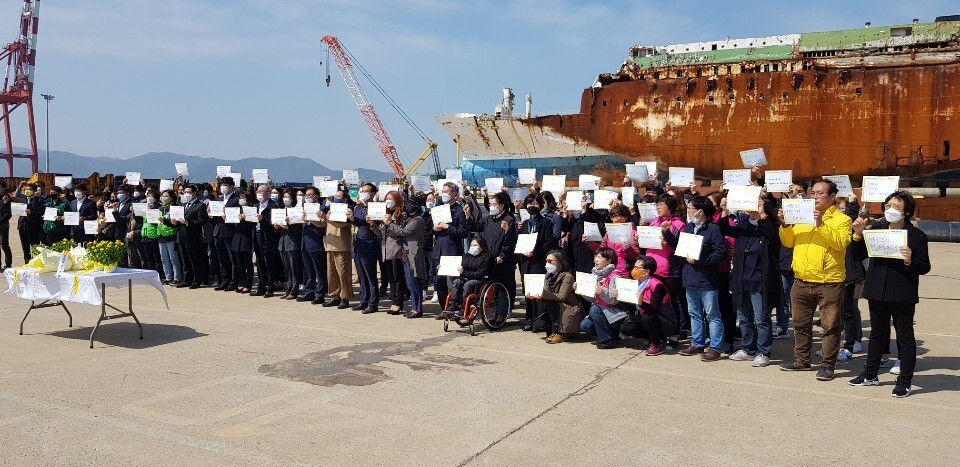 마스크를 쓴 추모객들이 16일 목포신항에서 ‘생명존중의 세상, 꽃으로 피어난 아이들’, ‘진실이 꽃피는 그 날을 만들어 주겠습니다’ 등 문구를 적은 손팻말을 들고 안전사회를 기원하고 있다. 독자 제공